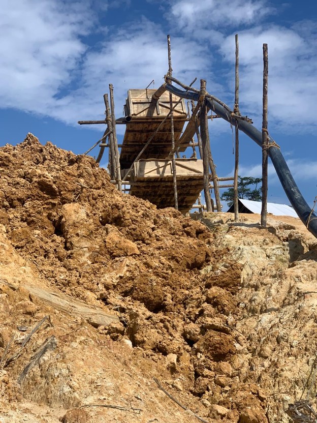 Excavator working in mining site with forest